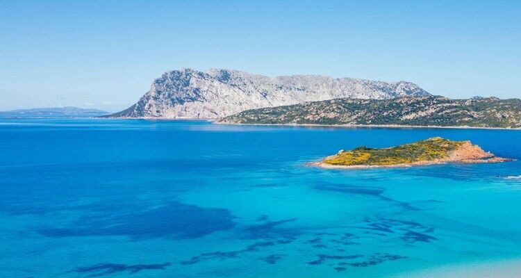 Clear turquoise water beside a rocky Sardinian coastline.